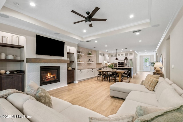 250 Ponder Cir, Yulee, FL 32097 - living room with ceiling fan, a raised ceiling, a glass covered fireplace, ornamental molding, and light wood-type flooring