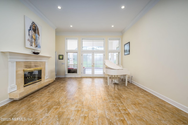 living area with french doors, baseboards, a tiled fireplace, crown molding, and recessed lighting