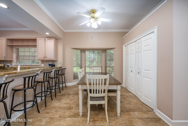 dining space featuring crown molding, ceiling fan, baseboards, and stone finish floors