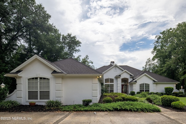 ranch-style house with stucco siding and roof with shingles