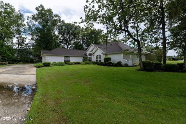 ranch-style home featuring driveway, a front lawn, and stucco siding