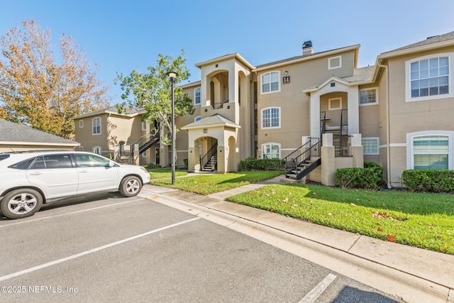 1701 The Greens Way Unit 1411, Jacksonville Beach, FL 32250 - multi unit property featuring uncovered parking, stucco siding, a front lawn, a chimney, and stairway