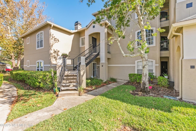 1701 The Greens Way Unit 1411, Jacksonville Beach, FL 32250 - multi unit property with stucco siding, stairs, a chimney, and a front yard