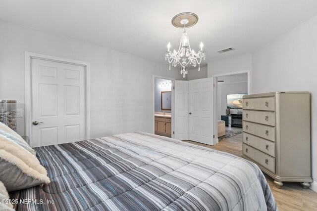 1701 The Greens Way Unit 1411, Jacksonville Beach, FL 32250 - bedroom featuring light wood-type flooring, a chandelier, a sink, and ensuite bath