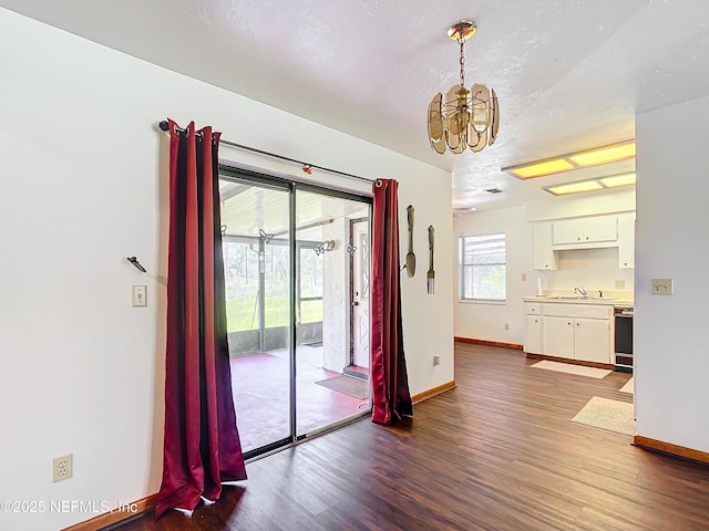 23063 SW Edgewater Blvd, Dunnellon, FL 34431 - unfurnished dining area with a chandelier, baseboards, dark wood finished floors, a sink, and a textured ceiling