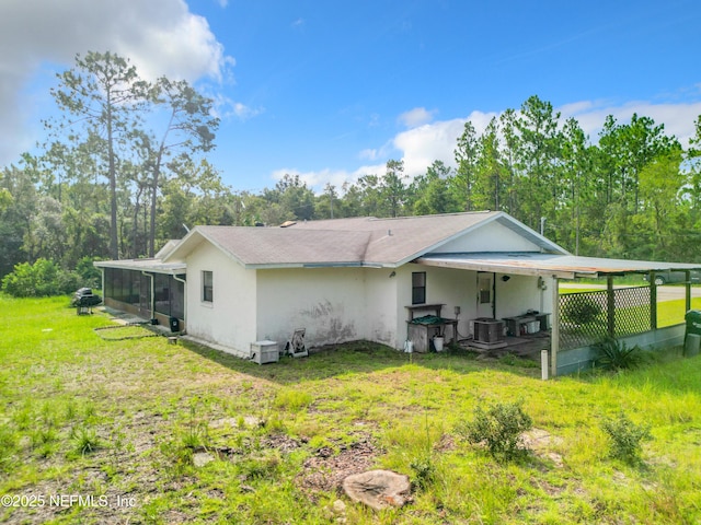 23063 SW Edgewater Blvd, Dunnellon, FL 34431 - rear view of property featuring a sunroom, central AC unit, a yard, and stucco siding