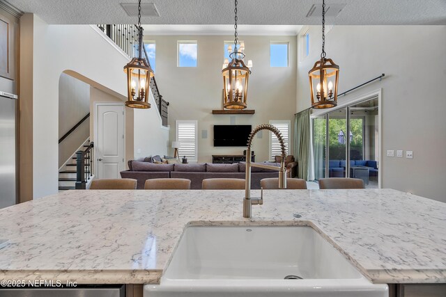 361 Amalurra Trl, Saint Johns, FL 32259 - kitchen featuring a sink, a chandelier, a textured ceiling, light stone counters, and hanging light fixtures