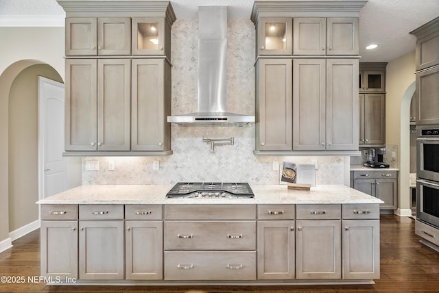 361 Amalurra Trl, Saint Johns, FL 32259 - kitchen featuring wall chimney exhaust hood, arched walkways, stainless steel appliances, baseboards, and dark wood-style floors