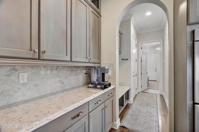 361 Amalurra Trl, Saint Johns, FL 32259 - kitchen featuring crown molding, arched walkways, light stone counters, decorative backsplash, and dark wood finished floors