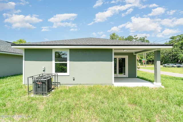 409 Willow Branch Ave, Jacksonville, FL 32254 - back of property featuring a lawn, stucco siding, and roof with shingles