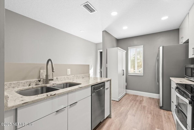 7142 Cypress Cove Rd Unit 39, Jacksonville, FL 32244 - kitchen featuring stainless steel appliances, a sink, light wood-style floors, white cabinets, and light stone counters