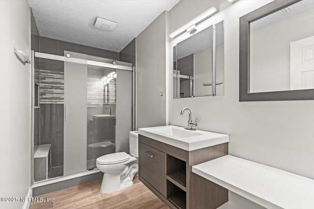 7142 Cypress Cove Rd Unit 39, Jacksonville, FL 32244 - bathroom with toilet, wood finished floors, a shower stall, vanity, and a textured ceiling