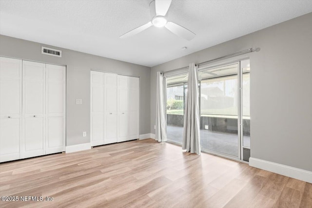 7142 Cypress Cove Rd Unit 39, Jacksonville, FL 32244 - unfurnished bedroom with access to outside, two closets, light wood-style floors, baseboards, and a textured ceiling
