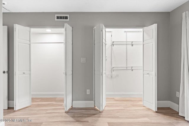 7142 Cypress Cove Rd Unit 39, Jacksonville, FL 32244 - unfurnished bedroom featuring a closet, a walk in closet, light wood-style floors, and baseboards