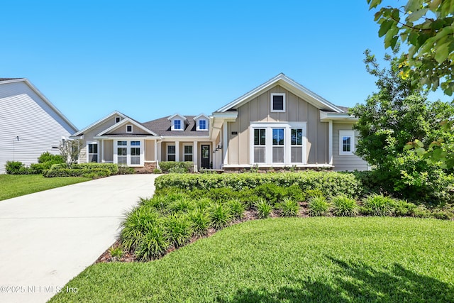 view of front of property featuring board and batten siding, a front yard, and concrete driveway