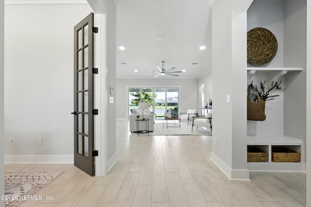 hallway with light wood-type flooring, crown molding, recessed lighting, and baseboards