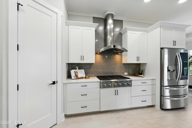 kitchen with stainless steel appliances, wall chimney exhaust hood, light countertops, decorative backsplash, and white cabinets