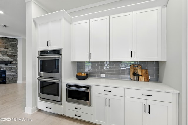 kitchen featuring double oven, backsplash, baseboards, and light countertops