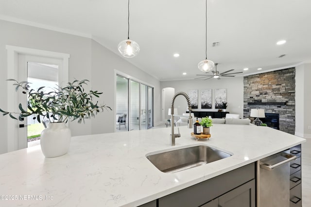kitchen with a sink, gray cabinetry, light stone countertops, a fireplace, and pendant lighting