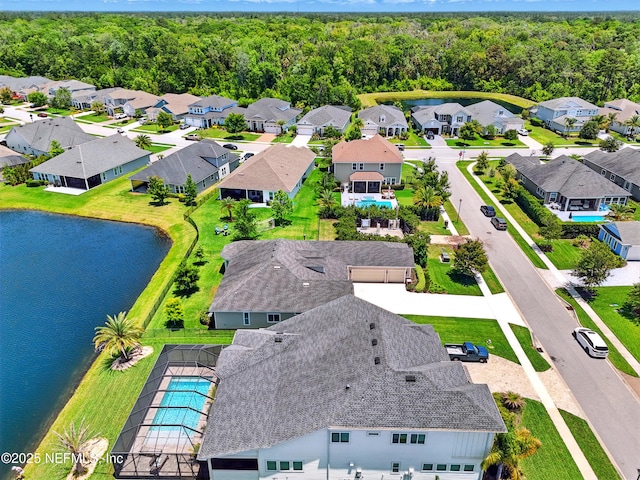aerial view of residential area with a pool, a nearby body of water, and a heavily wooded area