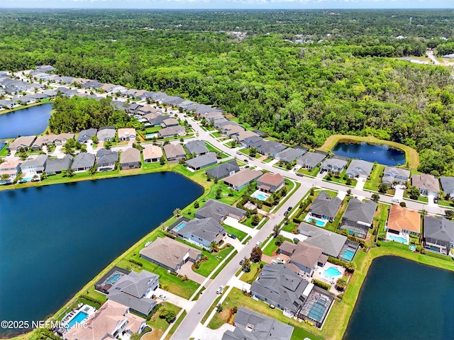 aerial view of property and surrounding area with nearby suburban area, a forest, and a nearby body of water