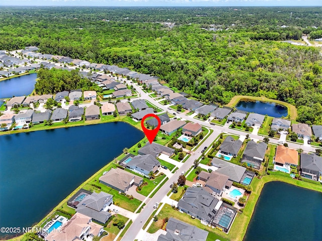aerial view of property's location with nearby suburban area, a heavily wooded area, and a nearby body of water