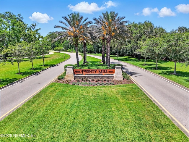 view of home's community featuring a yard, view of wooded area, and driveway