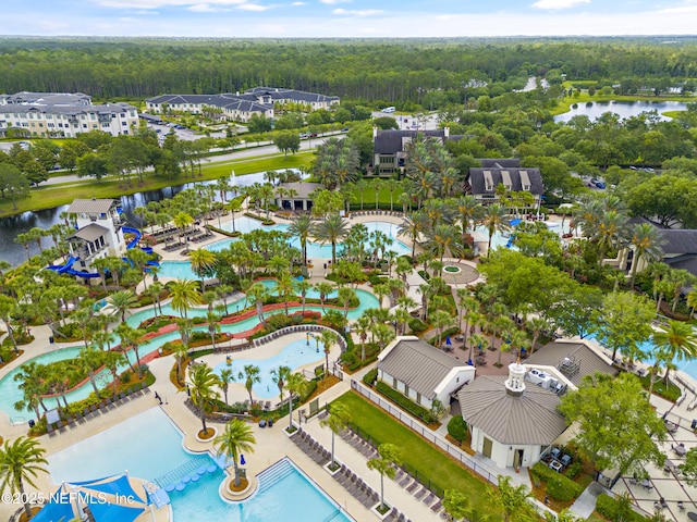 bird's eye view of a heavily wooded area, a pool area, and a large body of water