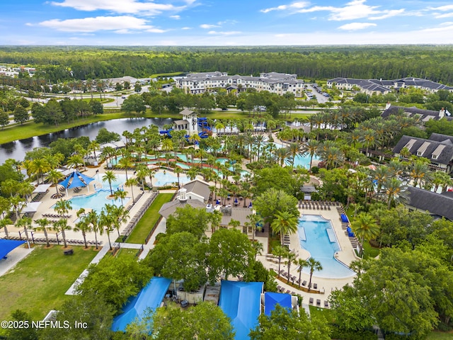bird's eye view of a pool, a heavily wooded area, and a nearby body of water