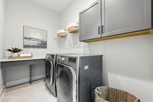 laundry area with washer and clothes dryer, light wood-style floors, cabinet space, and baseboards