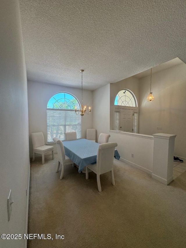dining room featuring light colored carpet, a textured ceiling, and a chandelier