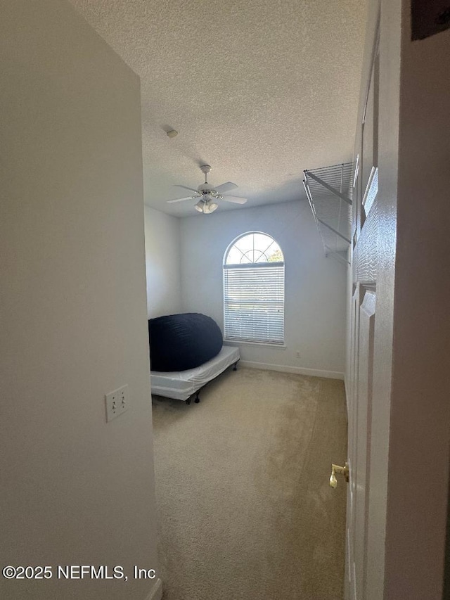unfurnished bedroom with carpet floors, a textured ceiling, baseboards, and a ceiling fan