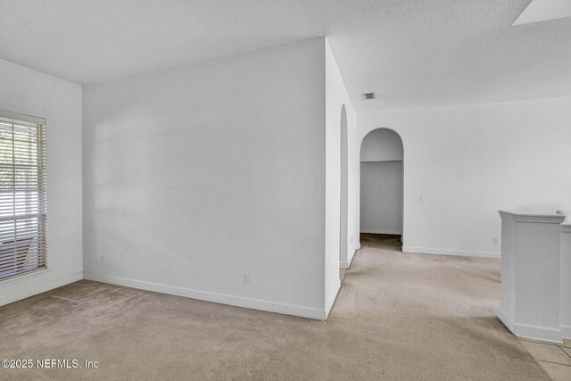809 Lotus Ln N, Fruit Cove, FL 32259 - empty room with arched walkways, light colored carpet, baseboards, and a textured ceiling