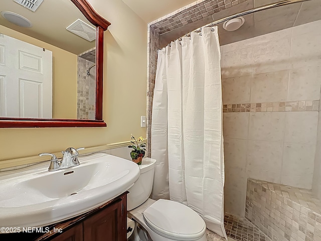 bathroom featuring tiled shower, toilet, and vanity