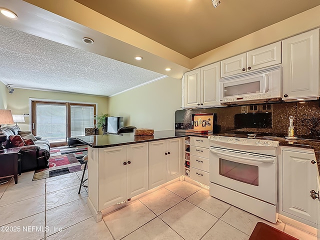 kitchen with white appliances, a peninsula, open floor plan, white cabinetry, and dark countertops