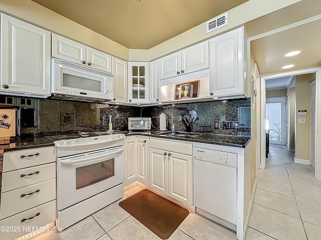 kitchen featuring white appliances, light tile patterned floors, dark countertops, and white cabinets