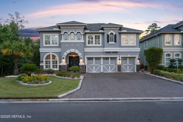 135 Tate Ln, Saint Johns, FL 32259 - view of front of property featuring an attached garage, decorative driveway, stucco siding, a lawn, and stone siding