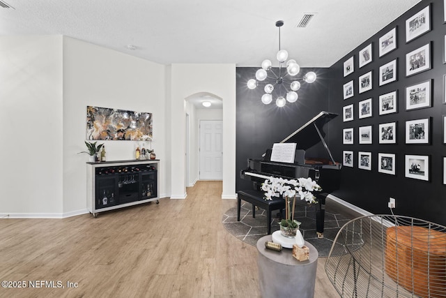 sitting room featuring arched walkways, wood finished floors, a chandelier, and baseboards