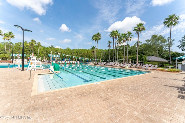 community pool featuring a patio and view of wooded area