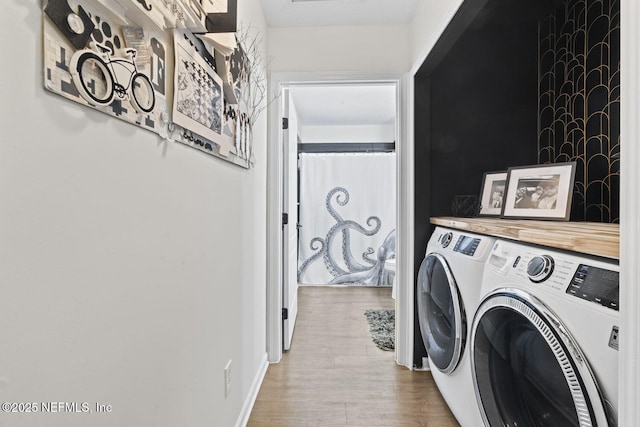 clothes washing area with washer and dryer and wood finished floors