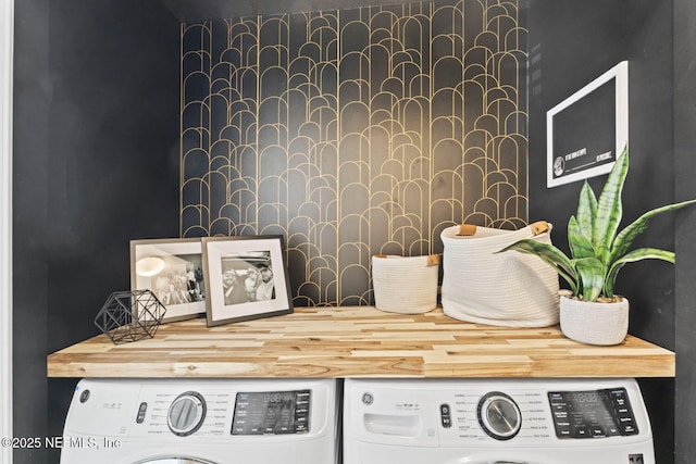 laundry view of separate washer and dryer, an accent wall, and wallpapered walls