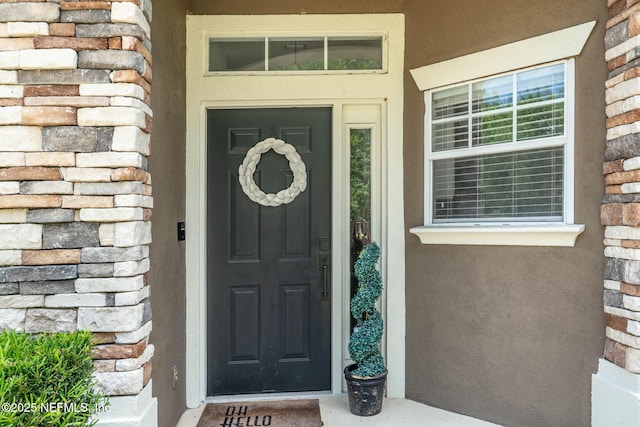 view of exterior entry featuring stucco siding, a porch, and stone siding
