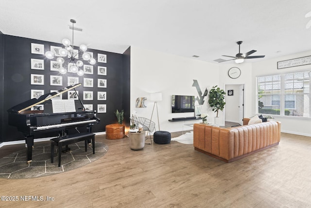 living room featuring wood finished floors, a ceiling fan, baseboards, and a chandelier