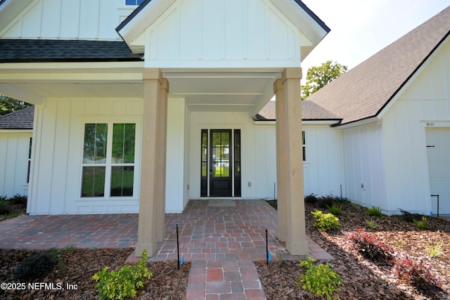 95121 N Ellis Landing Rd, Fernandina Beach, FL 32034 - doorway to property featuring board and batten siding, roof with shingles, and an attached garage