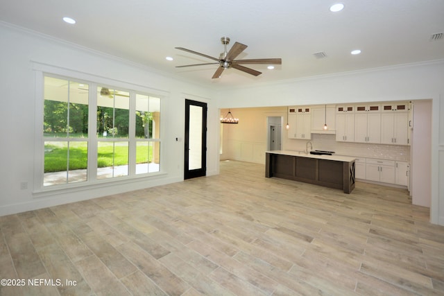 95121 N Ellis Landing Rd, Fernandina Beach, FL 32034 - kitchen with a ceiling fan, crown molding, light countertops, an island with sink, and white cabinets