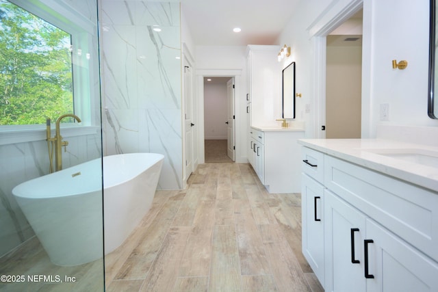 95121 N Ellis Landing Rd, Fernandina Beach, FL 32034 - full bathroom with a freestanding tub, two vanities, wood finished floors, and recessed lighting