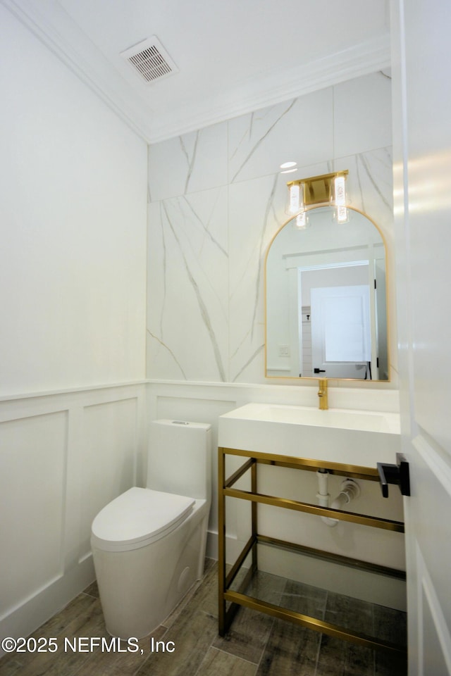 95121 N Ellis Landing Rd, Fernandina Beach, FL 32034 - half bathroom with toilet, vanity, a decorative wall, and wood finished floors