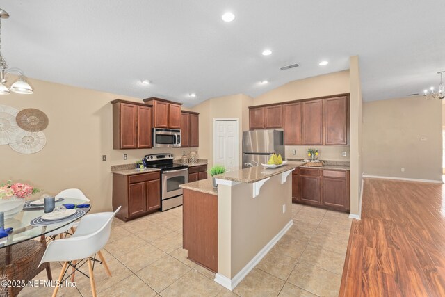 467 S Aberdeenshire Dr, Saint Johns, FL 32259 - kitchen with stainless steel appliances, a chandelier, light stone counters, light tile patterned floors, and vaulted ceiling