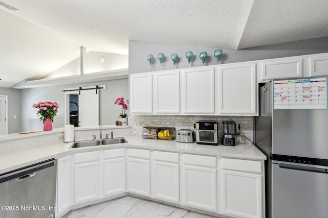 3100 Hickory Glen Dr, Orange Park, FL 32065 - kitchen featuring appliances with stainless steel finishes, lofted ceiling, a sink, a barn door, and white cabinetry