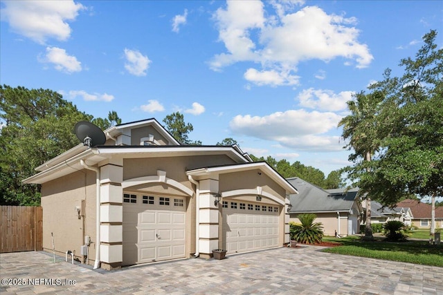 8719 Derry Dr, Jacksonville, FL 32244 - view of front facade with stucco siding, decorative driveway, fence, and an attached garage